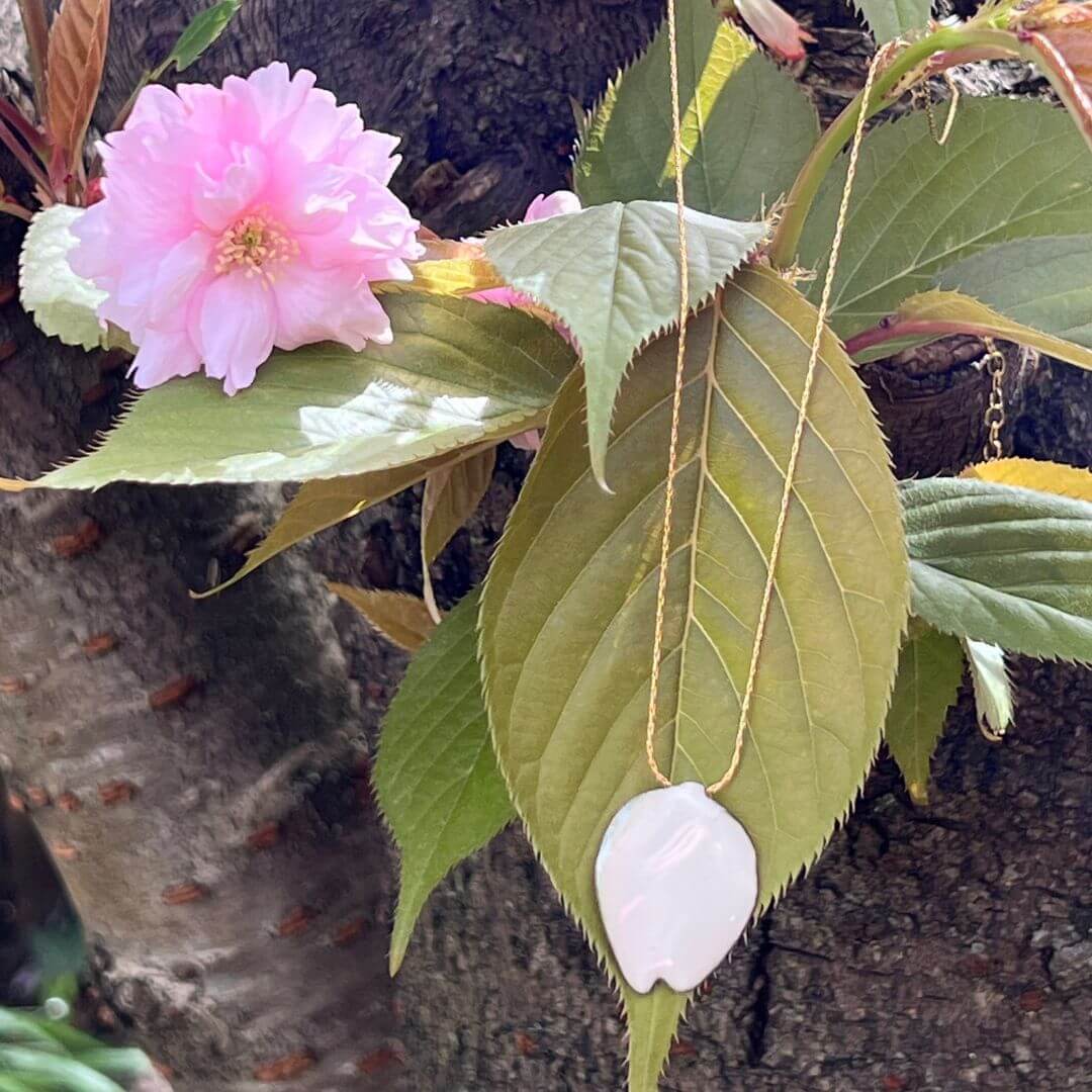 Eleganz der Einfachheit, nur ein Kirschblütenblatt emailliert. Anhänger aus Sakura-Blütenblatt auf einem blühenden Kirschblatt.