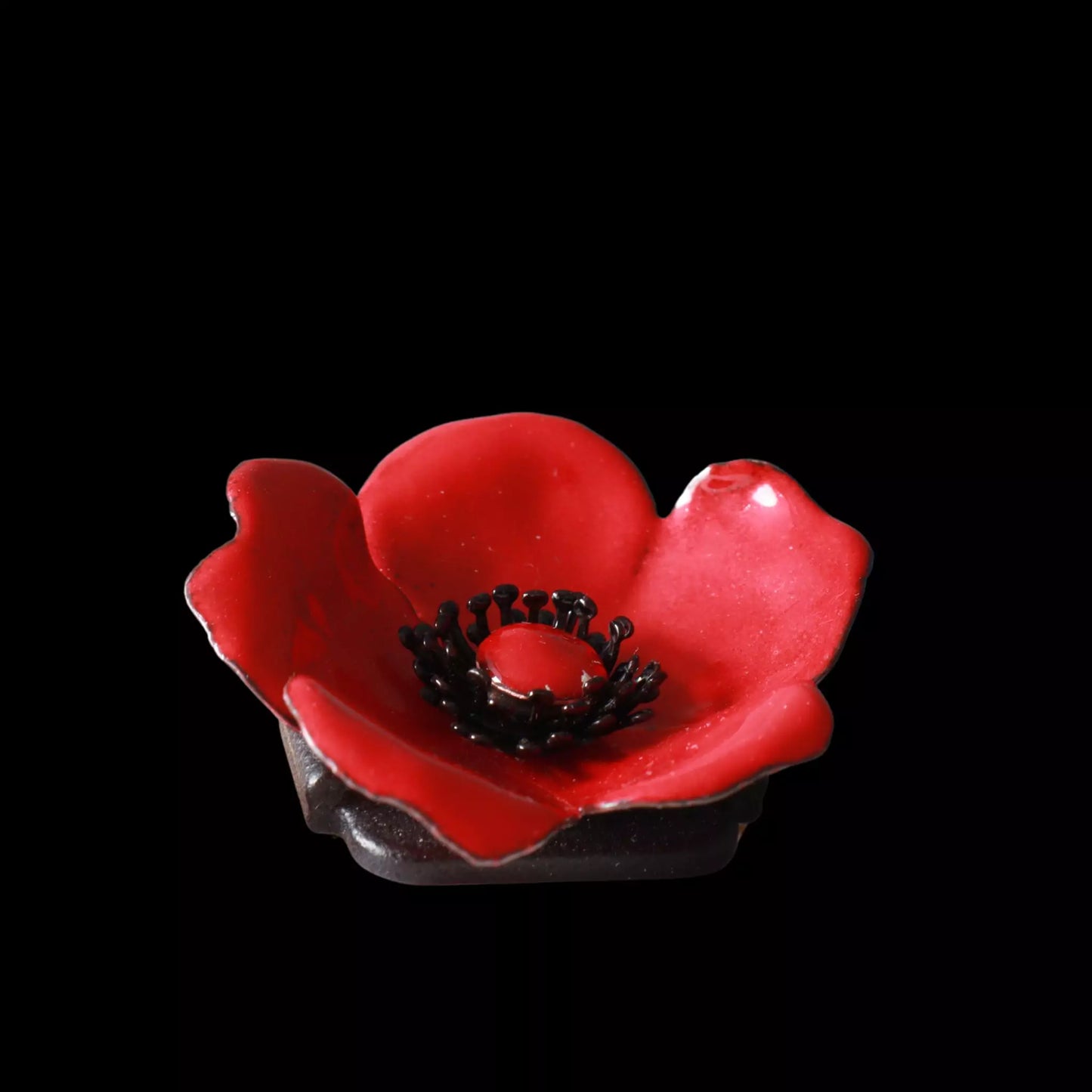 Florale Brosche aus roter Emaille mit Lichtreflexen. Black Hintergrund