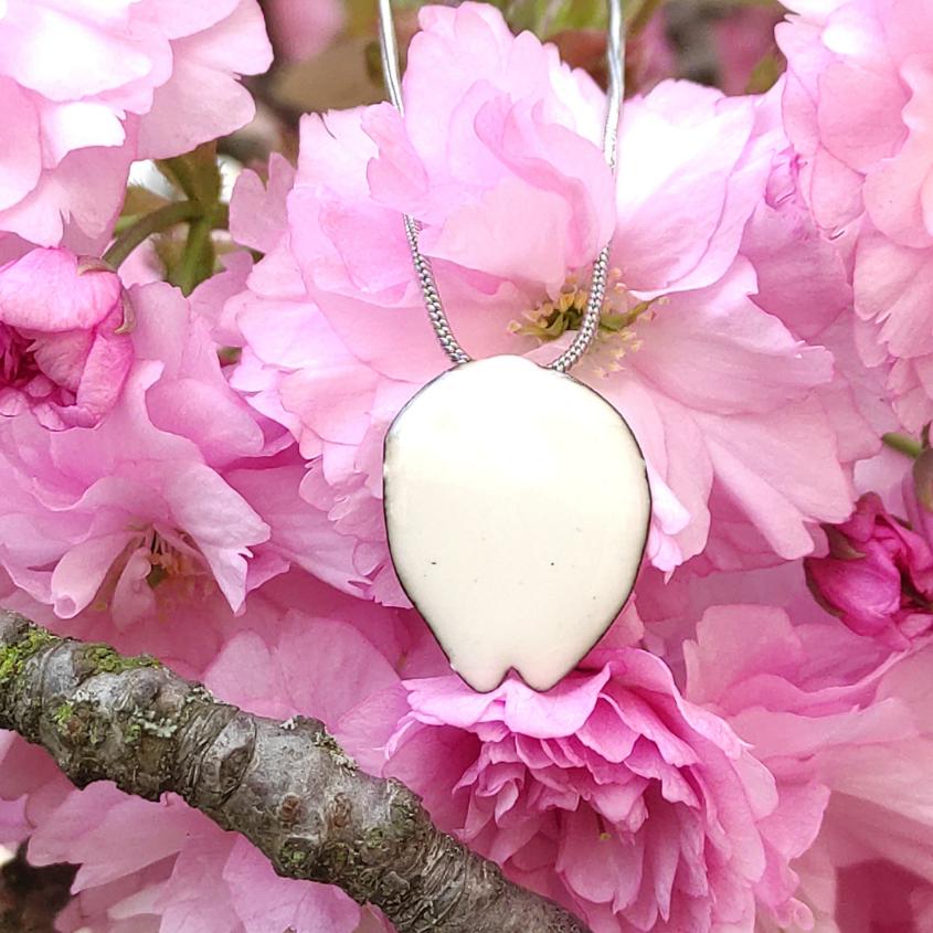 Sakura emailliertes Blütenblatt, Schmuckstück und Kette aus Edelstahl fotografiert mit Kirschblüten. Entdecken Sie den Sakura-Anhänger, ein raffiniertes Schmuckstück, inspiriert von japanischen Kirschblüten. Perfekt für einen eleganten und lässigen Stil.