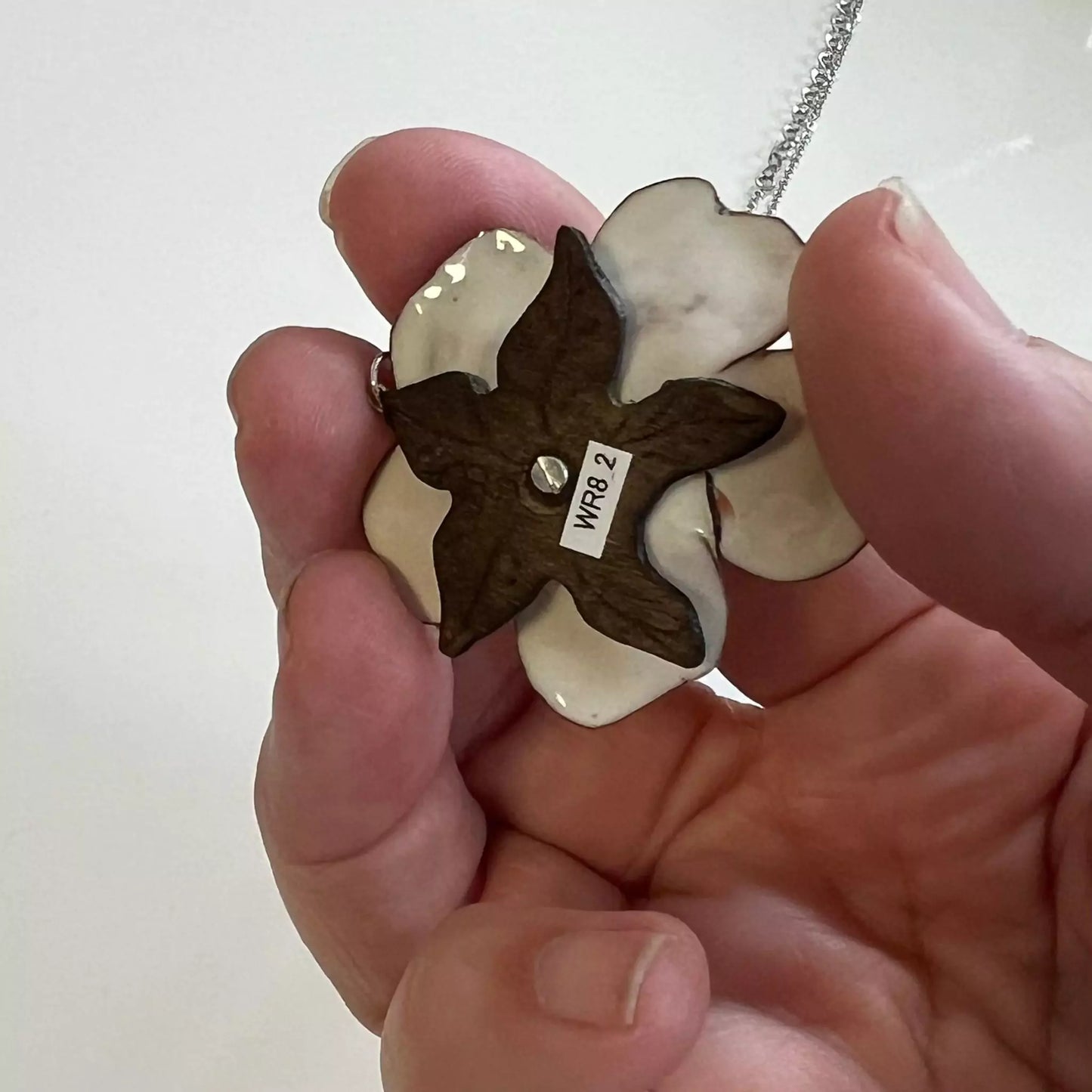 Florales Schmuckstück handgefertigt Marianne, emaillierter Rosenanhänger mit Kelchblättern aus Holz und Edelstahlkette auf weißem Hintergrund