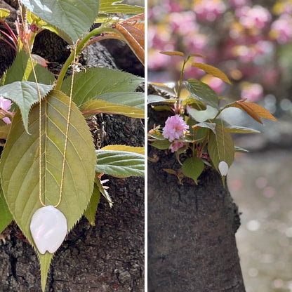 Anhänger aus Sakura-Blütenblatt auf einem blühenden Kirschblatt. Naturschmuck elegant 