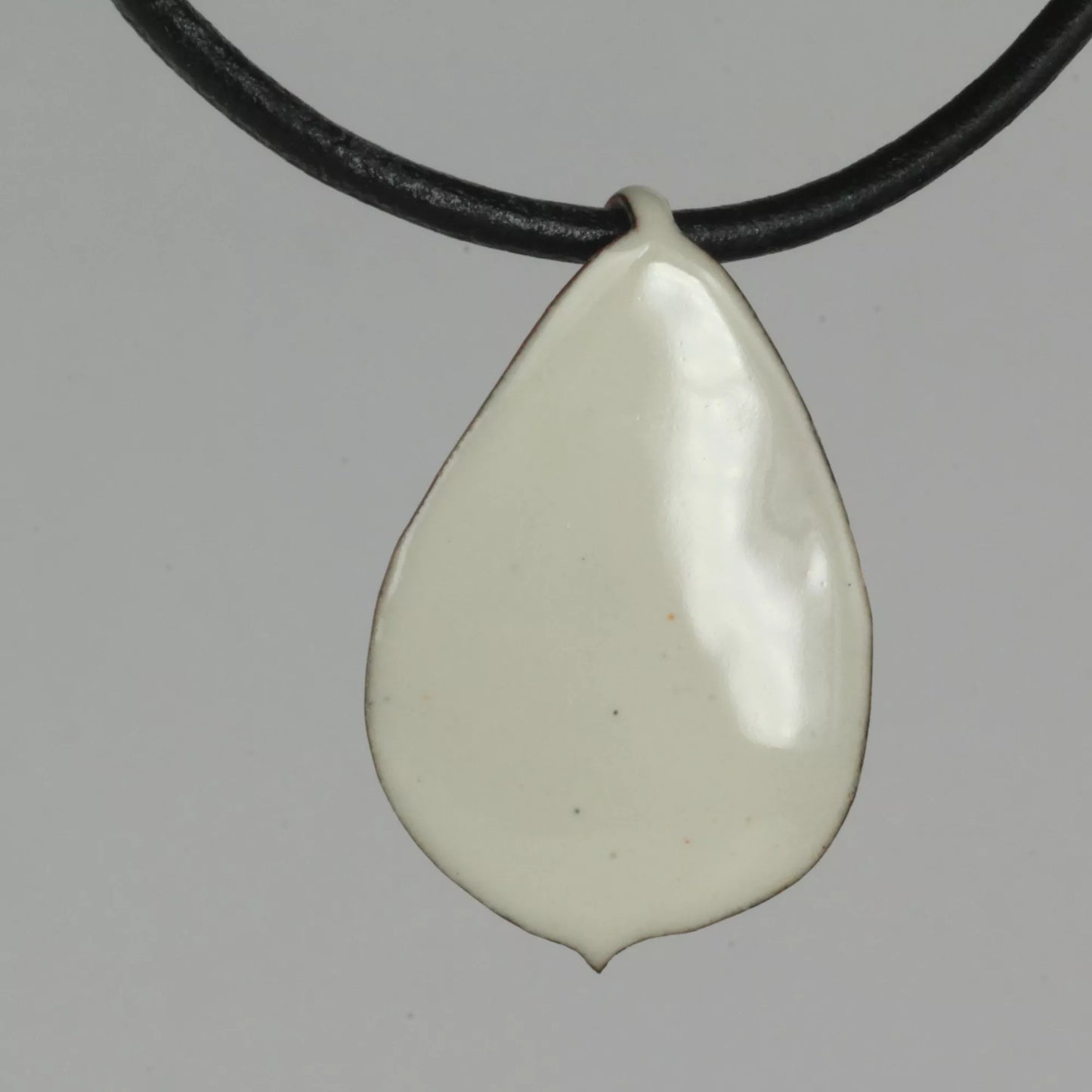 Creme Emaille Anhänger Rosenblütenblatt mit schwarzem Lederband 3mm, Vorderansicht auf grauem Hintergrund