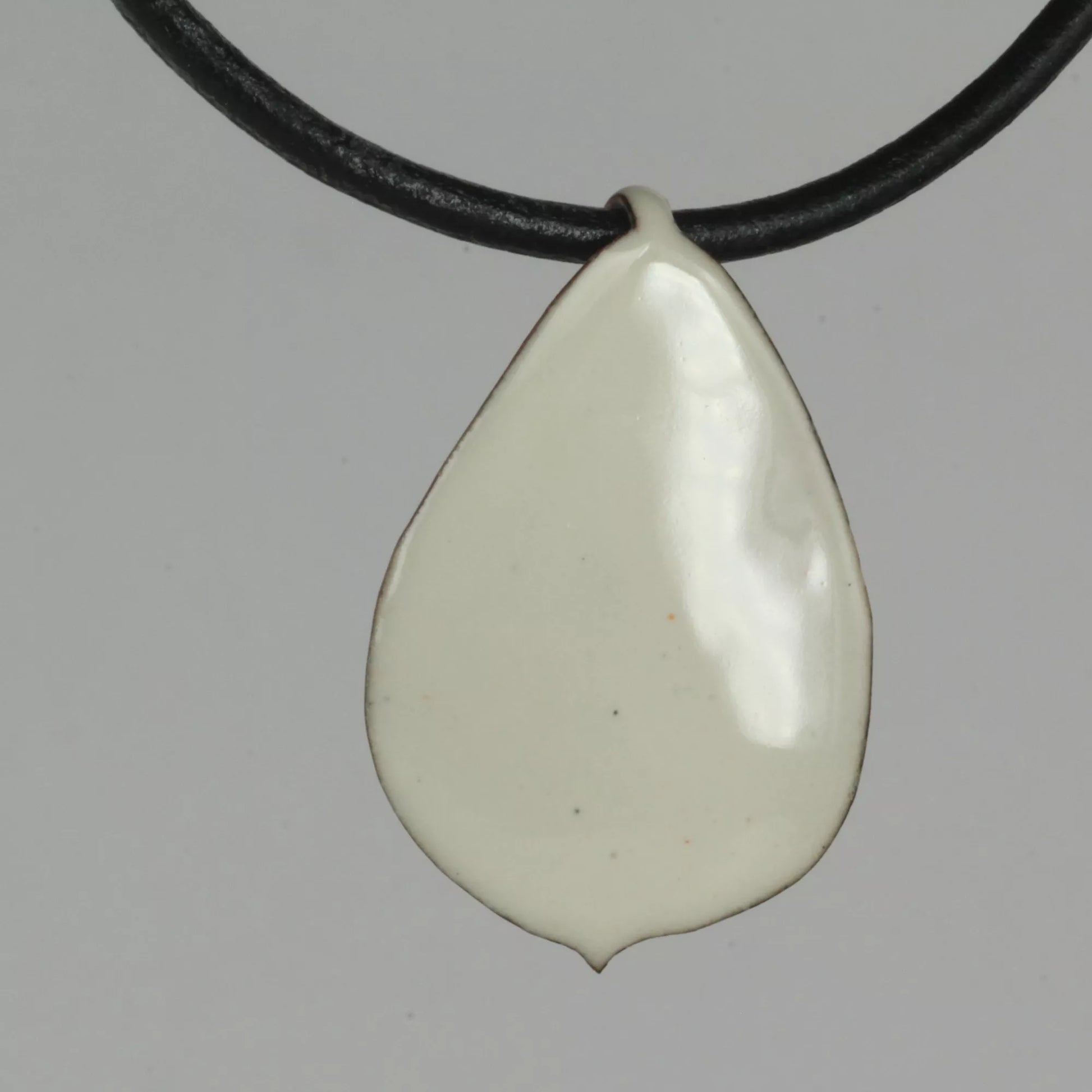 Creme Emaille Anhänger Rosenblütenblatt mit schwarzem Lederband 3mm, Vorderansicht auf grauem Hintergrund
