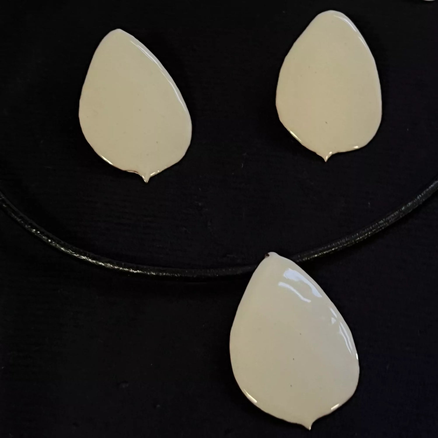 Vergleich Lions Rose Kollektion: Anhänger PR8-1 mit Lederband und Ohrstecker PR8-11 in Creme auf schwarzem Hintergrund